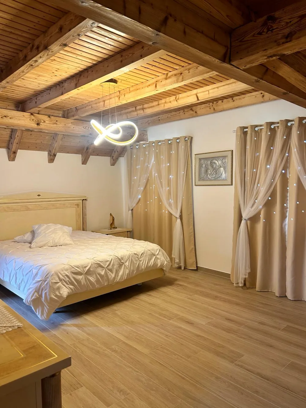 Chambre sous charpente apparente avec parquet clair.