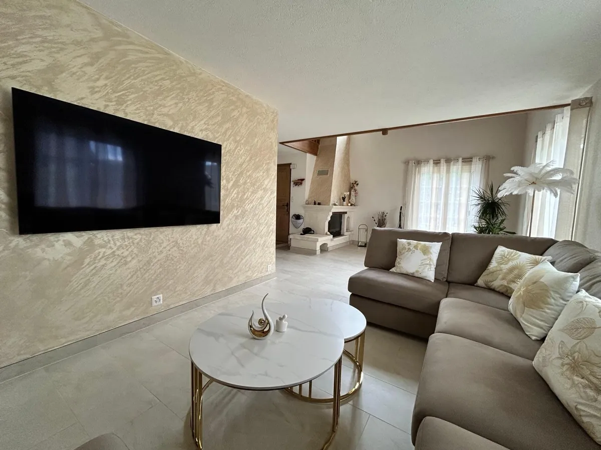 Salon avec mur en enduit décoratif et écran encastré.