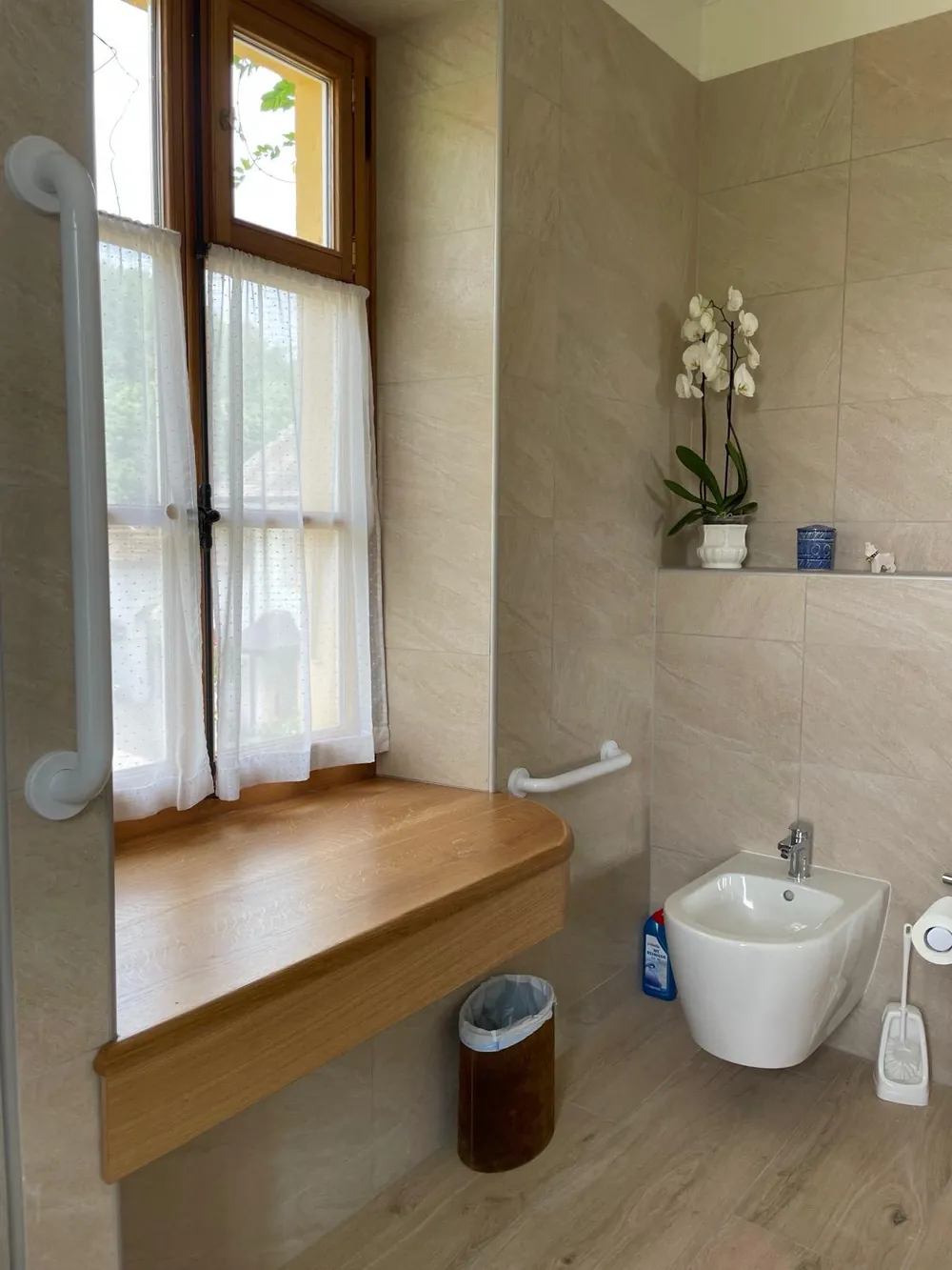 Salle de bains claire avec plan en pierre et grande fenêtre.