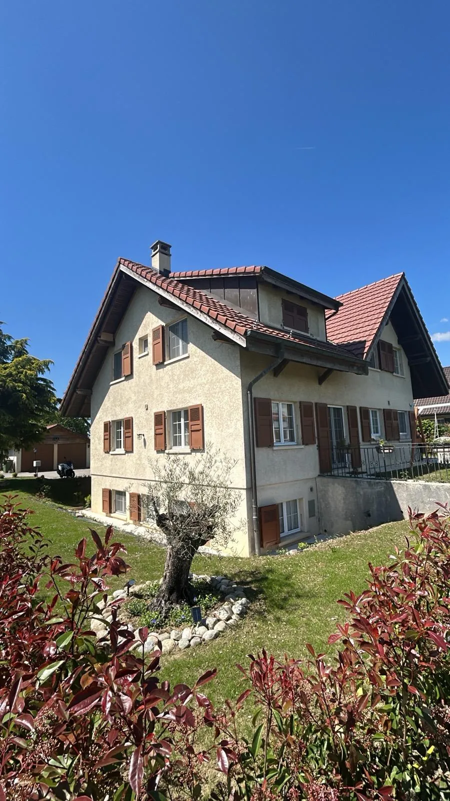 Villa en pierre claire entourée d'arbustes.
